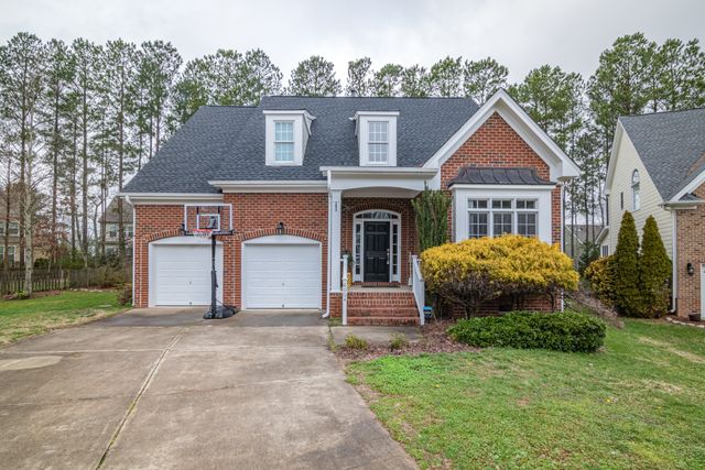 Brick suburban home with garage and basketball hoop in a peaceful neighborhood.