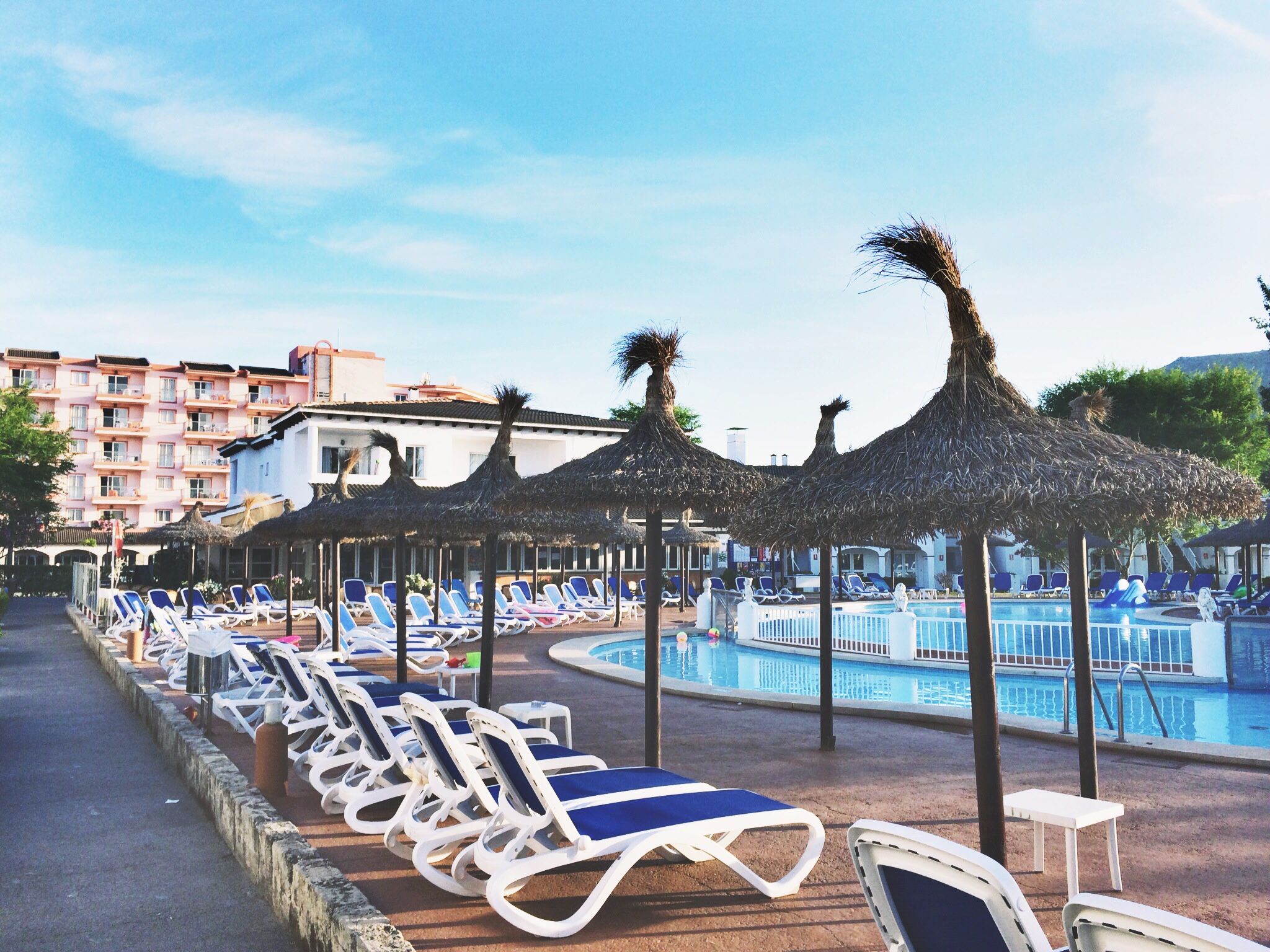 A resort poolside area with straw umbrellas and sun loungers, perfect for a tropical vacation.